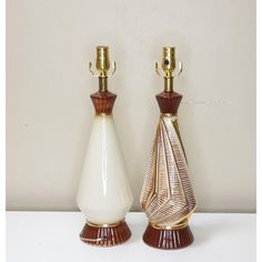 two white and brown vases sitting next to each other on top of a table