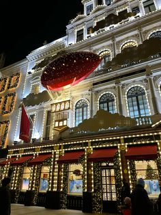 a large building with christmas lights on it's sides and an umbrella hanging from the roof