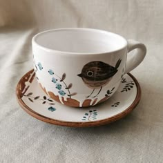 a cup and saucer with a bird painted on it