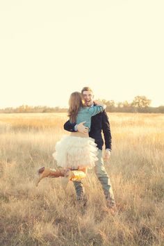 a man holding a woman in the middle of a field