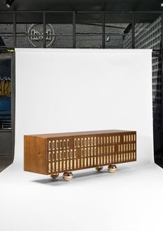 a wooden cabinet sitting on wheels in front of a white backdrop with black and yellow letters