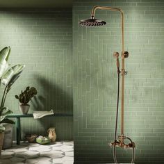 a green tiled bathroom with a shower head and hand held shower faucet in the corner