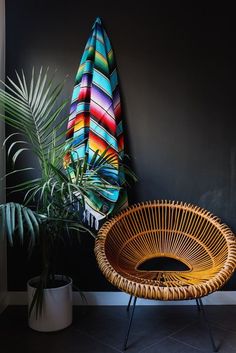 a wicker chair sitting next to a potted plant and a surfboard on the wall