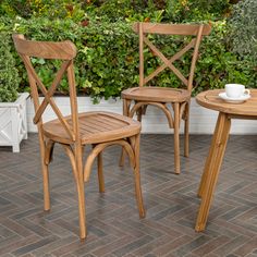 two wooden chairs sitting next to each other near a table with a cup on it