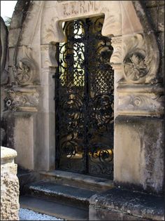 an ornate iron gate in front of a stone building