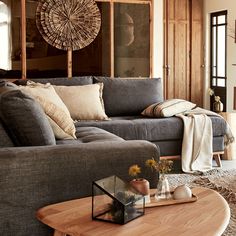 a living room filled with furniture and pillows on top of a wooden table in front of a window