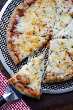 a pizza sitting on top of a white plate next to a red and white checkered table cloth