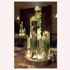 an arrangement of candles and flowers in glass vases