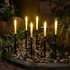 there are many candles that are lit up in the night time setting on some rocks