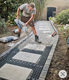 a man laying on the ground in front of a house with cement blocks and tools