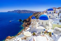 the blue domed buildings are overlooking the water and cliffs in oiai, greece