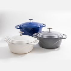 three different colored casserole dishes on a white background with one blue and the other grey