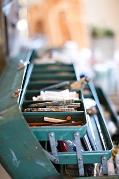 an old green toolbox filled with tools and other items sitting on top of a table