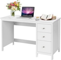 a laptop computer sitting on top of a white desk next to a vase with flowers