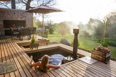 a woman laying in a hot tub on top of a wooden deck next to an open fire pit