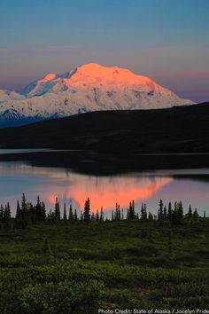 the snow capped mountain is reflected in the still waters of this lake at sunset or dawn