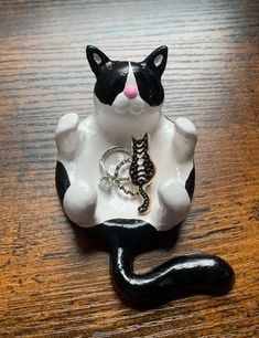 a black and white cat figurine with a ring on it's tail