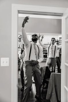 a group of men standing around each other in front of a doorway with their arms up