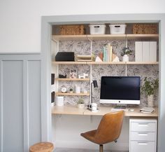 a desk with a computer on top of it and some shelves above the desk in front of it