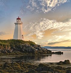 a light house sitting on top of a rocky hill next to the ocean