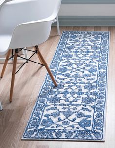 a blue and white area rug with an ornate design on the floor next to a chair