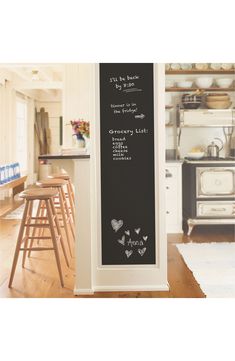 a chalkboard sign in the middle of a kitchen next to stools and tables