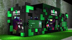 a green and black exhibit booth with neon lights on the sides, grass in front of it