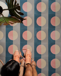 a woman is sitting on the floor with her feet up and wearing high heels in front of a patterned wall