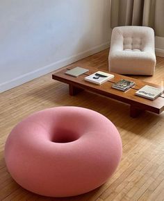 a pink bean bag chair sitting on top of a wooden floor next to a coffee table