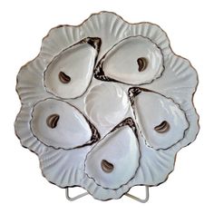 four oysters on a white plate sitting on a metal stand with holes in the middle