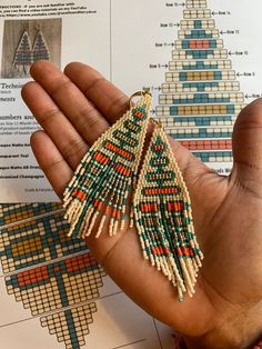 a hand holding a pair of beaded earrings