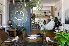 a living room filled with lots of furniture and plants on top of a wooden floor