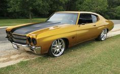 an orange and black muscle car parked on the side of the road in front of some trees