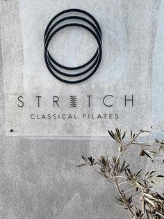 the sign for stretch classical pilates is displayed in front of a plant