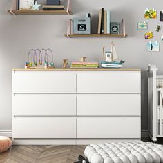 a baby's room with a crib, bookshelf and dresser