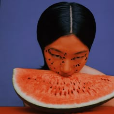 a woman with black dots on her face is eating a slice of watermelon