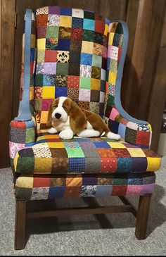 a brown and white dog laying on top of a patchwork chair in a room