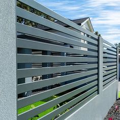 a modern fence with metal slats on the sides and green grass in the front yard