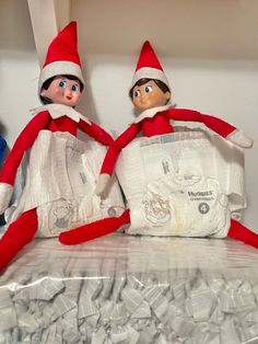 two elfs sitting on top of a pile of diapers next to each other