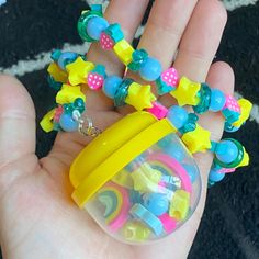 a hand holding a small plastic toy in it's palm with lots of beads