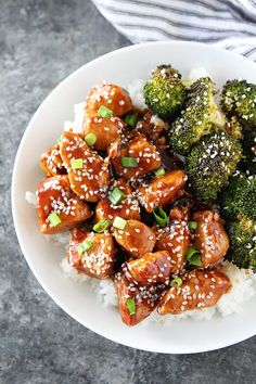 a white plate topped with chicken and broccoli covered in sesame seed flakes