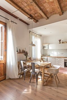 an open kitchen and dining room with wood flooring, white walls and wooden ceiling