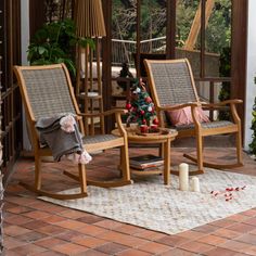 two rocking chairs sitting on top of a patio next to a christmas tree and potted plant