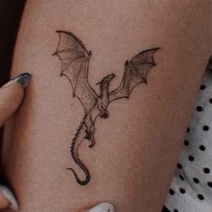 a woman's arm with a tattoo on it that has a dragon drawn on it