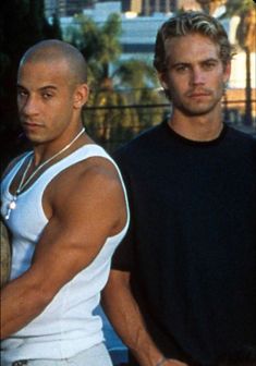 two men standing next to each other holding tennis racquets