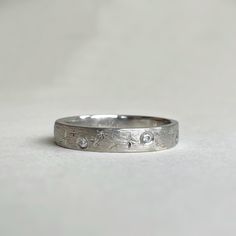 a close up of a ring on a white surface with small diamonds in the middle