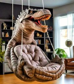 an inflatable dinosaur chair is hanging from a rope and has its mouth open