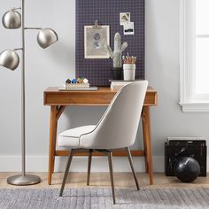 a desk with a chair, lamp and pictures on the wall in front of it