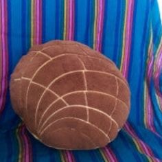 a brown ball sitting on top of a blue and pink striped cloth covered chair cushion