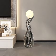 a metal sculpture sitting on top of a white table next to a tv monitor and lamp